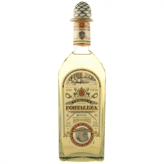 Fortaleza Reposado Tequila in its signature clear glass bottle topped with the hand-blown glass agave piña stopper, holding light golden 100% Blue Agave tequila